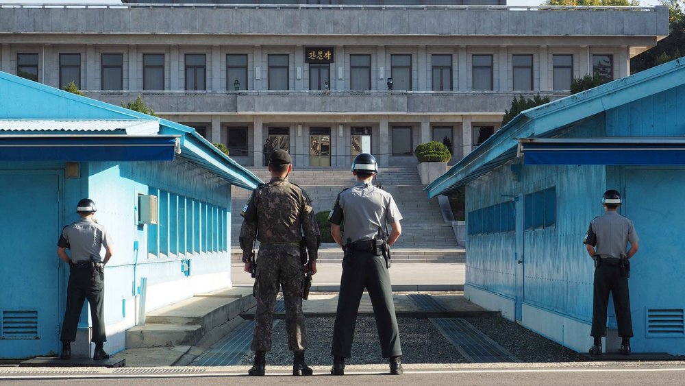 UNC soldiers standing guard in the Joint Security Area (JSA) between the blue buildings. View from the south. To the rear is the Panmungak building, located in the DPRK.
